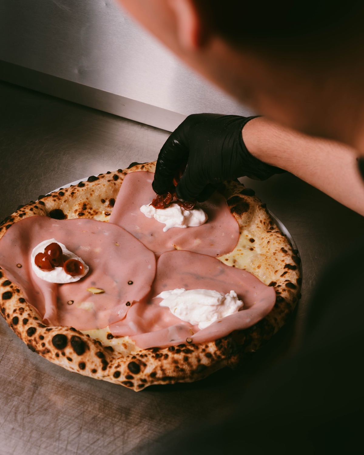 Mortadella-pizzaa kootaan käsin