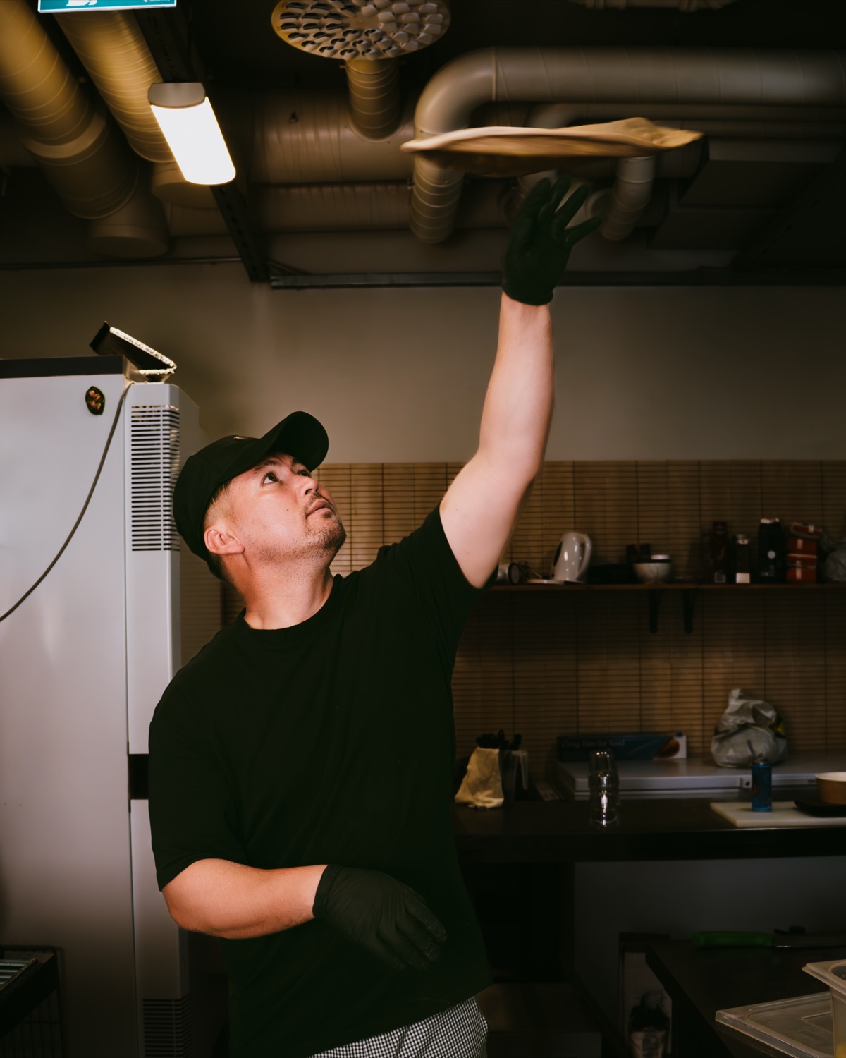 Pizzaiolo pyörittää taikinaa ilmassa